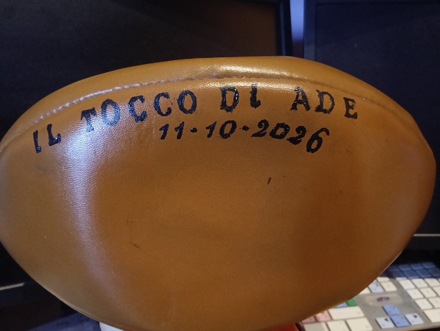 Pallone da rugby con la scritta realizzata a mano ‘Il Tocco di Ade’ e la data 11 ottobre 2026, preparato per raccogliere le firme delle Pioniere del rugby femminile italiano.